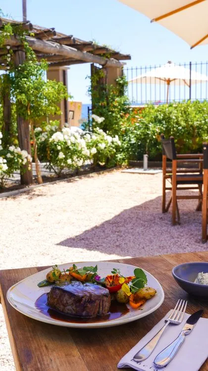 Table en terrasse avec vue mer et plat de viande