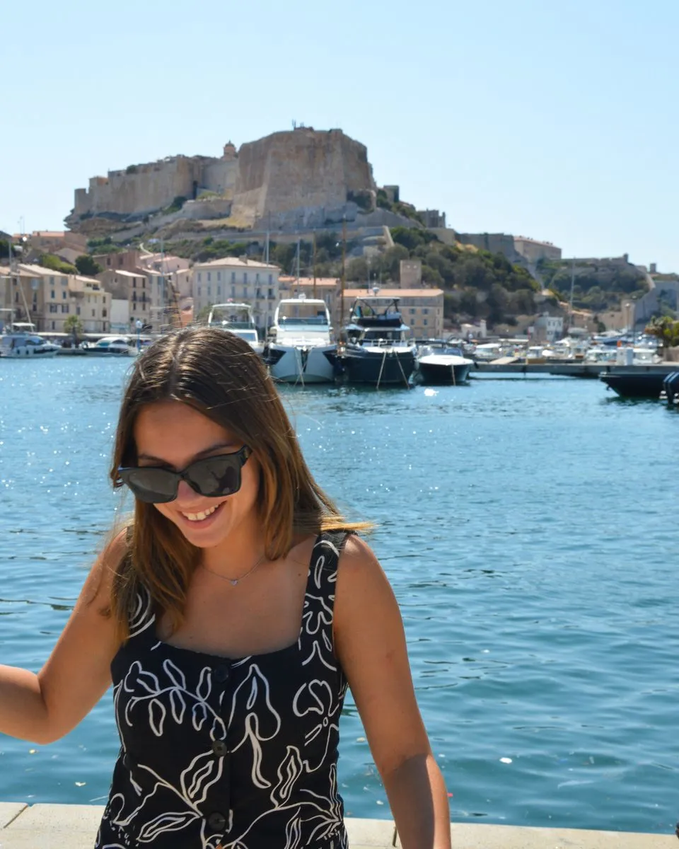Clémence devant un port avec vue sur une citadelle